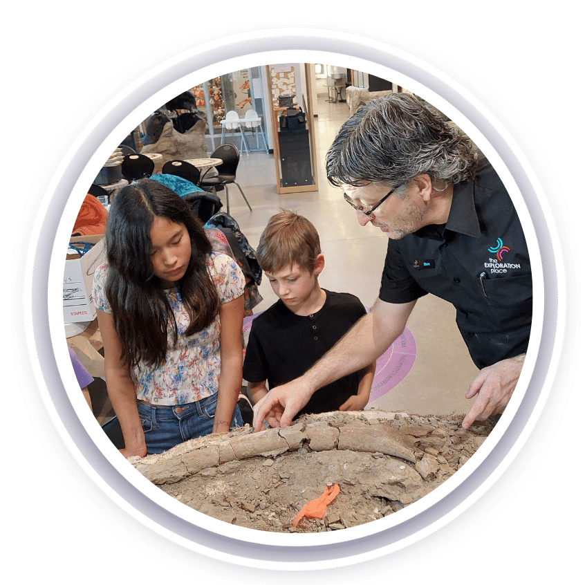 A man and two children looking at a dinosaur fossil